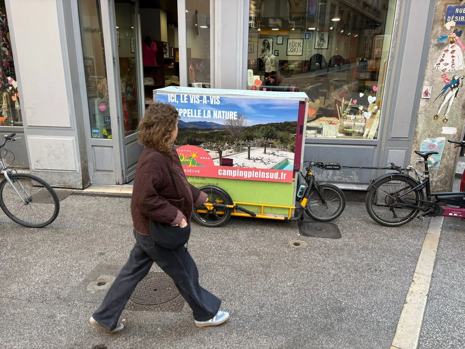 Vélo publicitaire LCDG stationné devant les vitrines d'une rue commerçante
