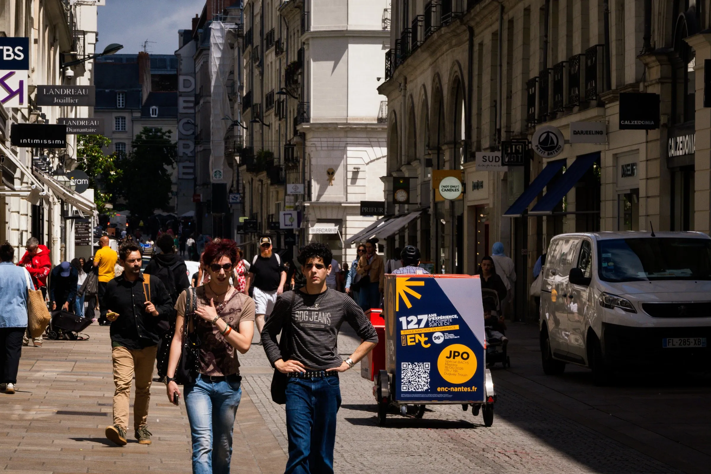Triporteur publicitaire LCDG au milieu d'une rue piétonne commerçante très fréquentée