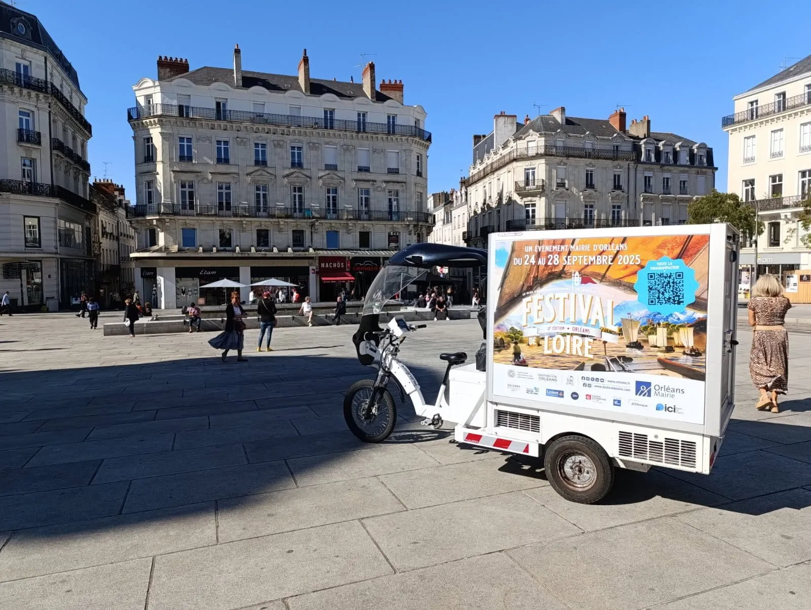 Triporteur publicitaire LCDG en campagne sur une place de centre-ville animée