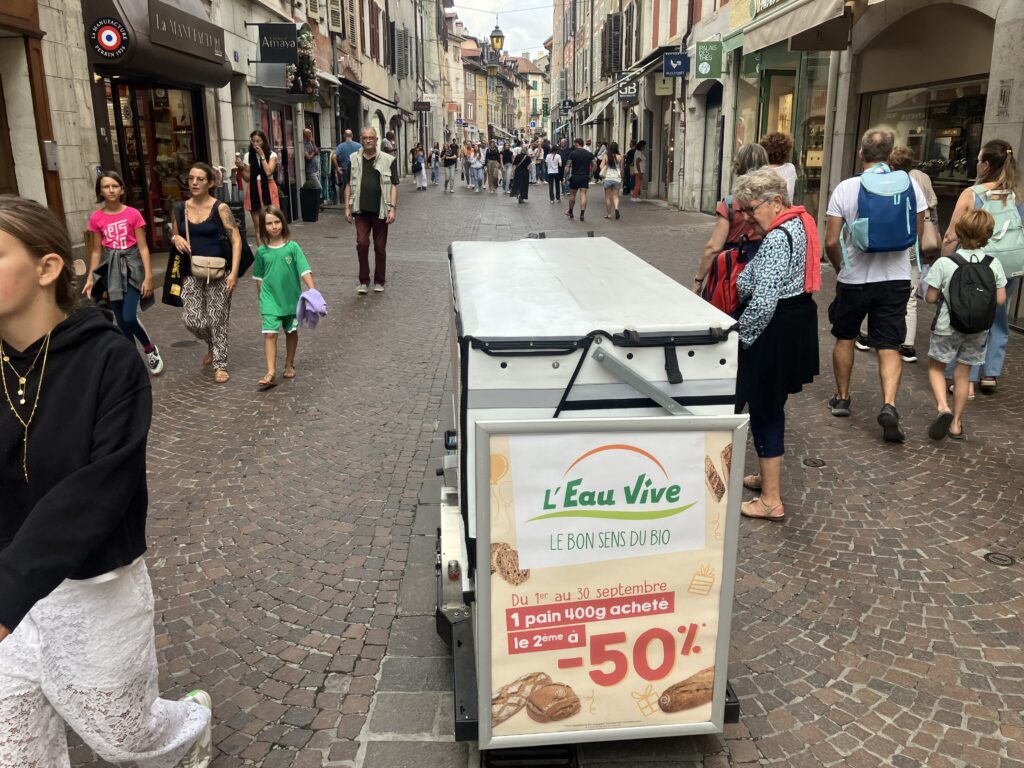 Vélo publicitaire arrêtant les passants dans la rue.